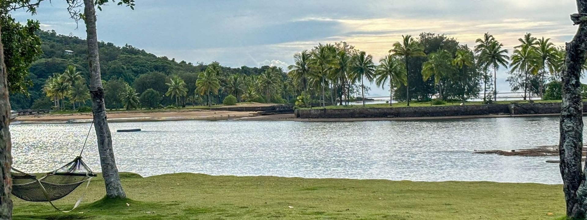 Green hammock on beach with palm trees and water at The Naviti Resort in Korolevu, Fiji