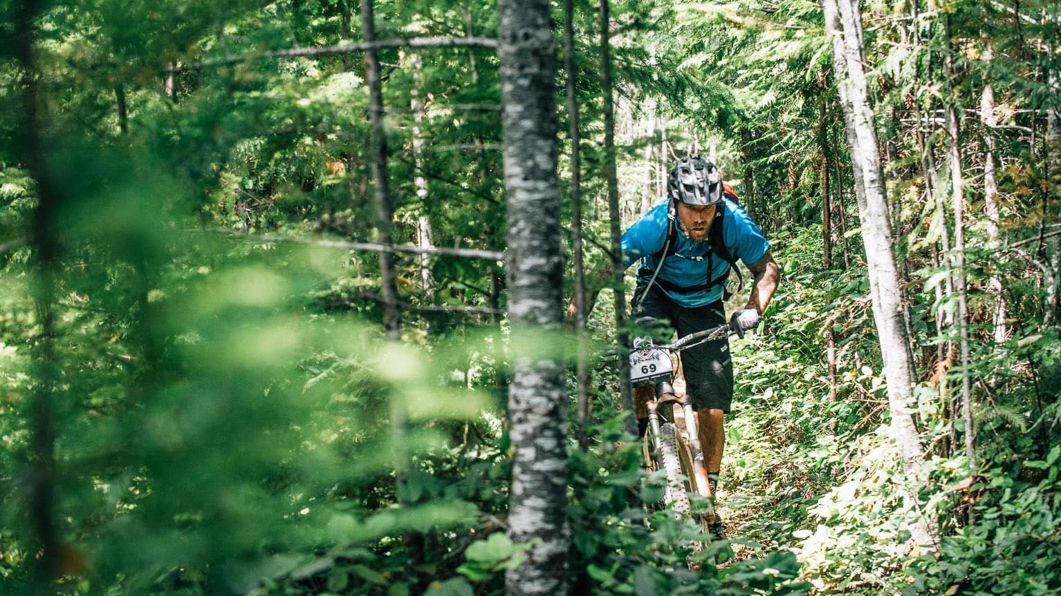 Mountain biker on a ride through trees near Chateaux Deer Valley