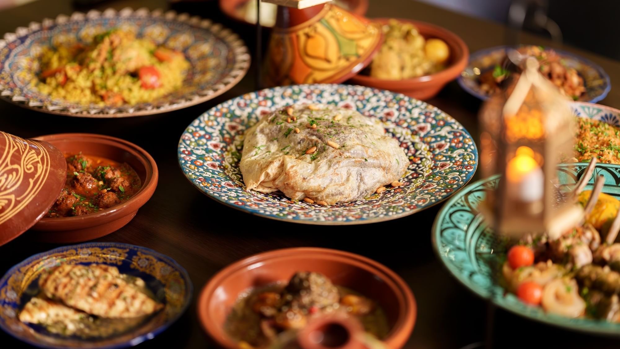 Vibrant Middle Eastern feast with rice, chicken, and stews, artfully served on decorative plates at Paramount Hotels