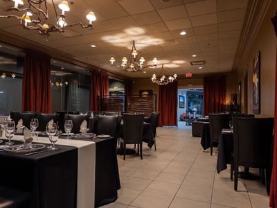 Elegant restaurant with set tables, chandeliers, and curtains at Carriage House Hotel Conference Centre