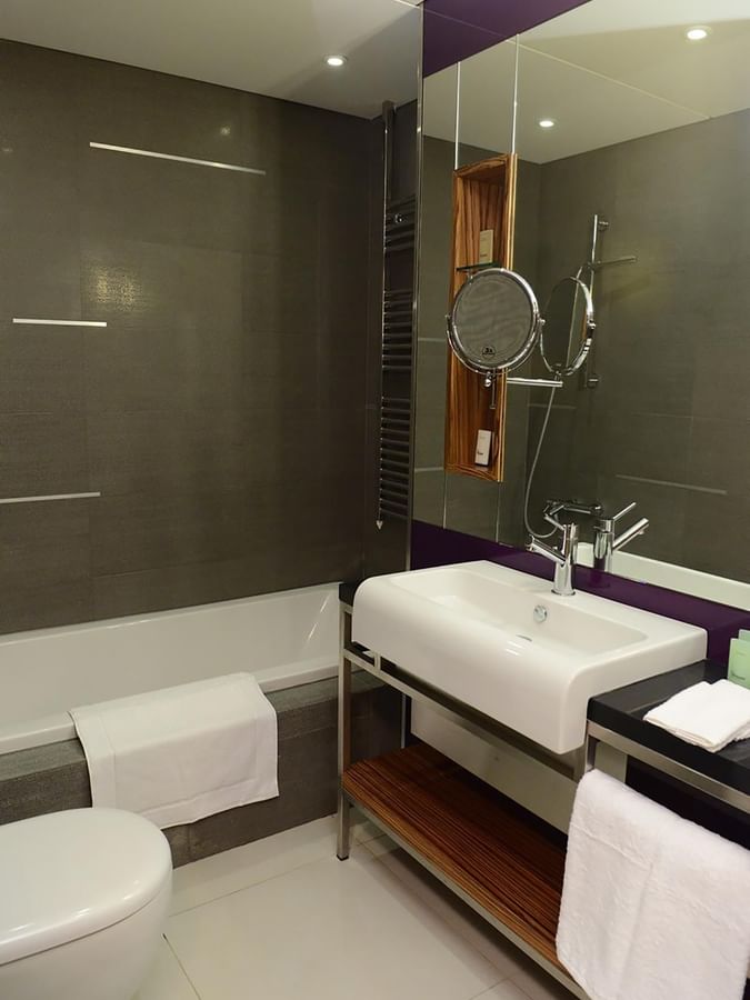 White basin by a soaking tub and chrome fixtures under a swivel mirror in Executive Room at Warwick Stone 55 - Beirut