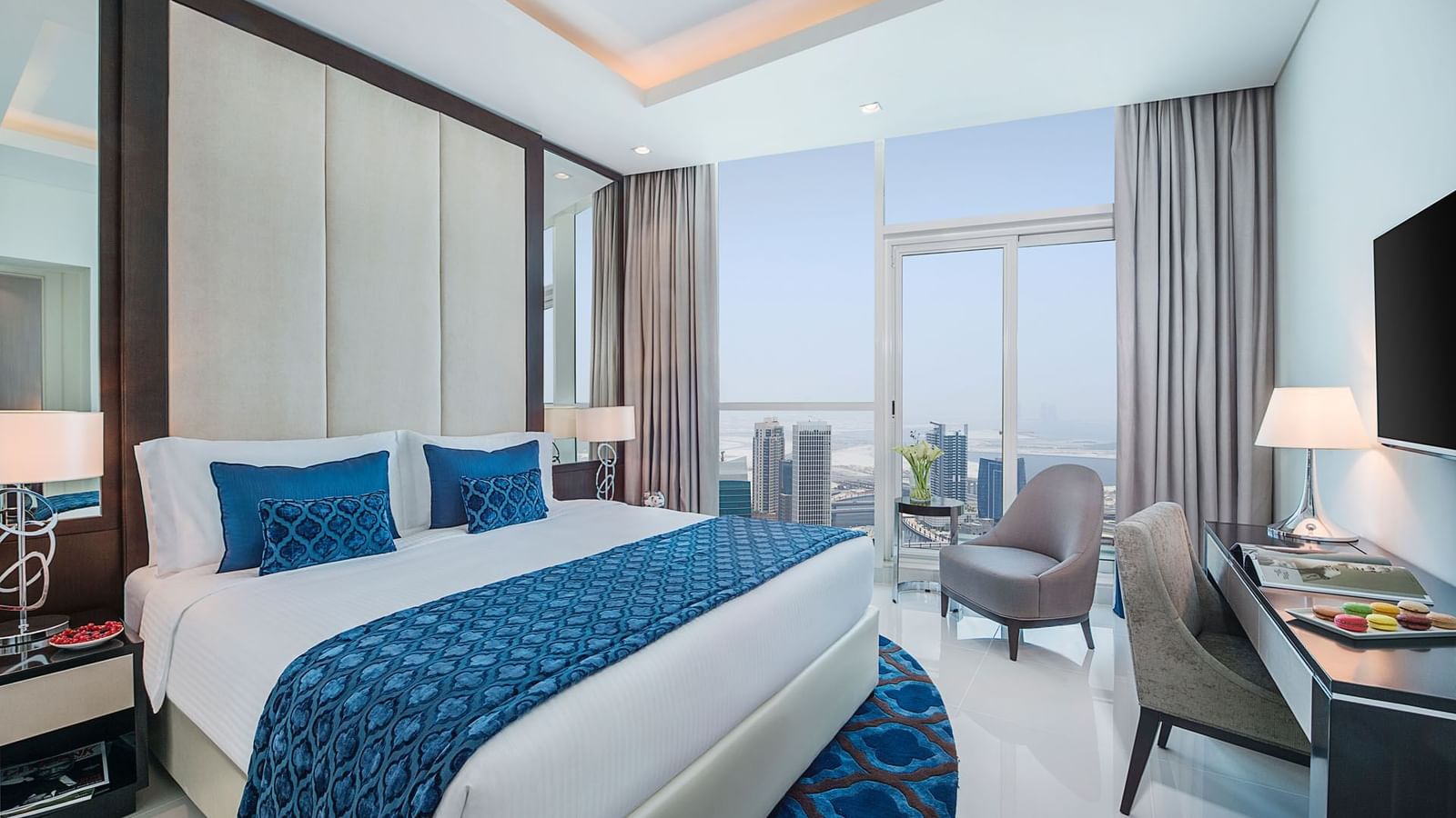 King-size bed by the window & a work desk in One Bedroom Suite at DAMAC Maison Distinction