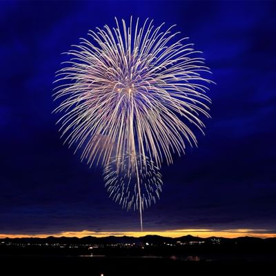 Feuerwerk in Form eines Sterns am Nachthimmel über einer beleuchteten Stadt.