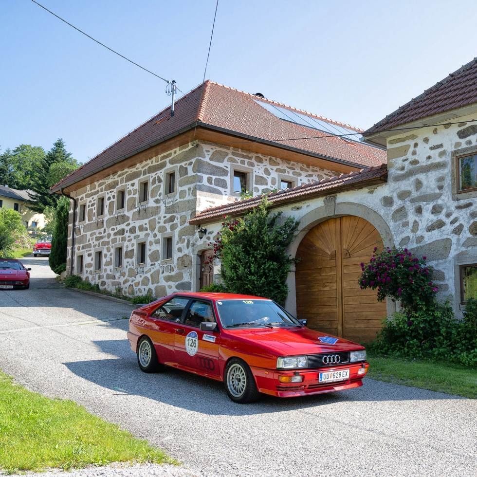 A red car parked in front of a gate at Falkensteiner Hotels