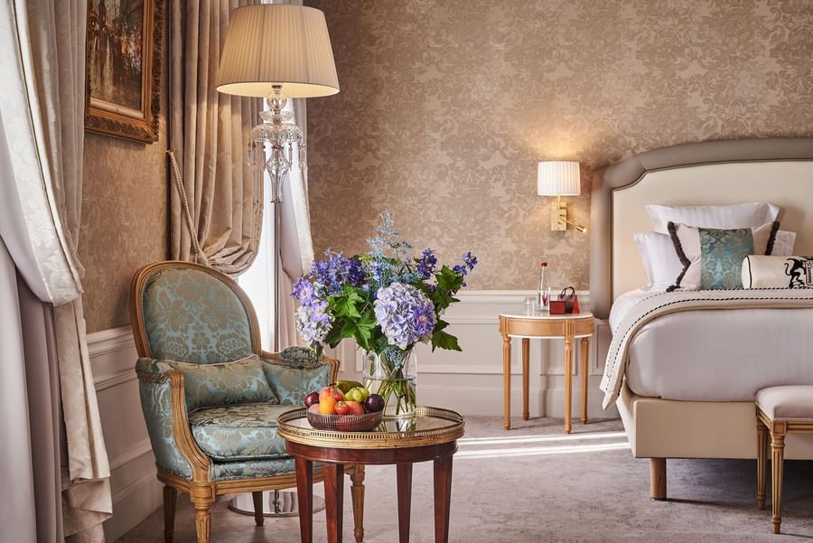 Bed with side table and couch near window in Prestige Suite – Rue de la Paix View at Hotel Westminster Paris 