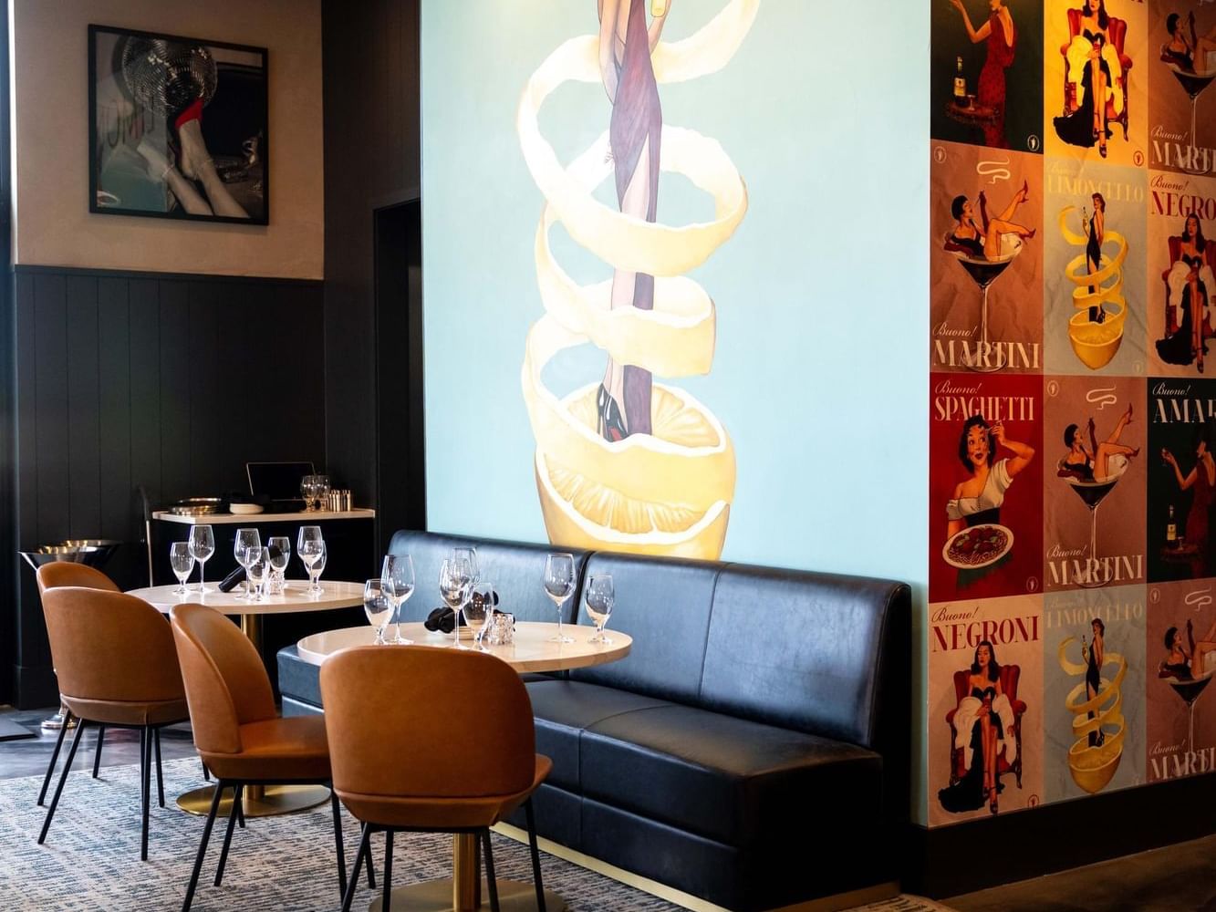 Dining set-up with two round tables & wall decor in The Rooftop Restaurant at The Artisan Hotel at Tuscan Village