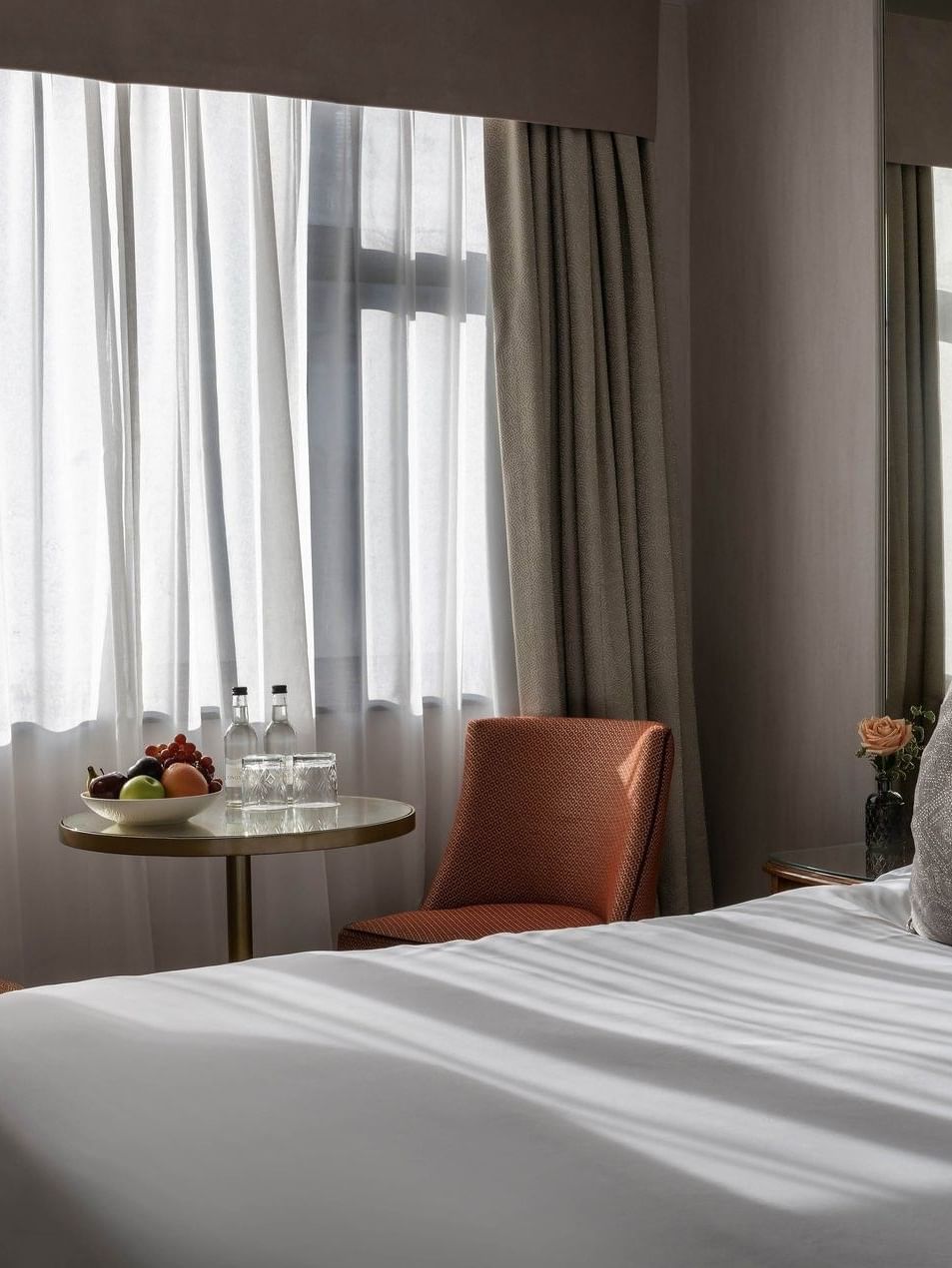 Cozy Standard Room with bed, pillows, fruit bowl, and window view at The Capital Hotel London.
