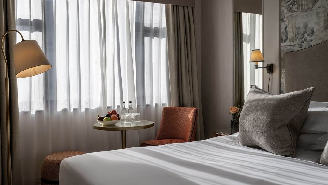 Cozy Standard Room with bed, pillows, fruit bowl, and window view at The Capital Hotel London.
