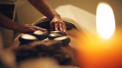 A masseuse giving a spa treatment with rocks at Hotel Sumaq