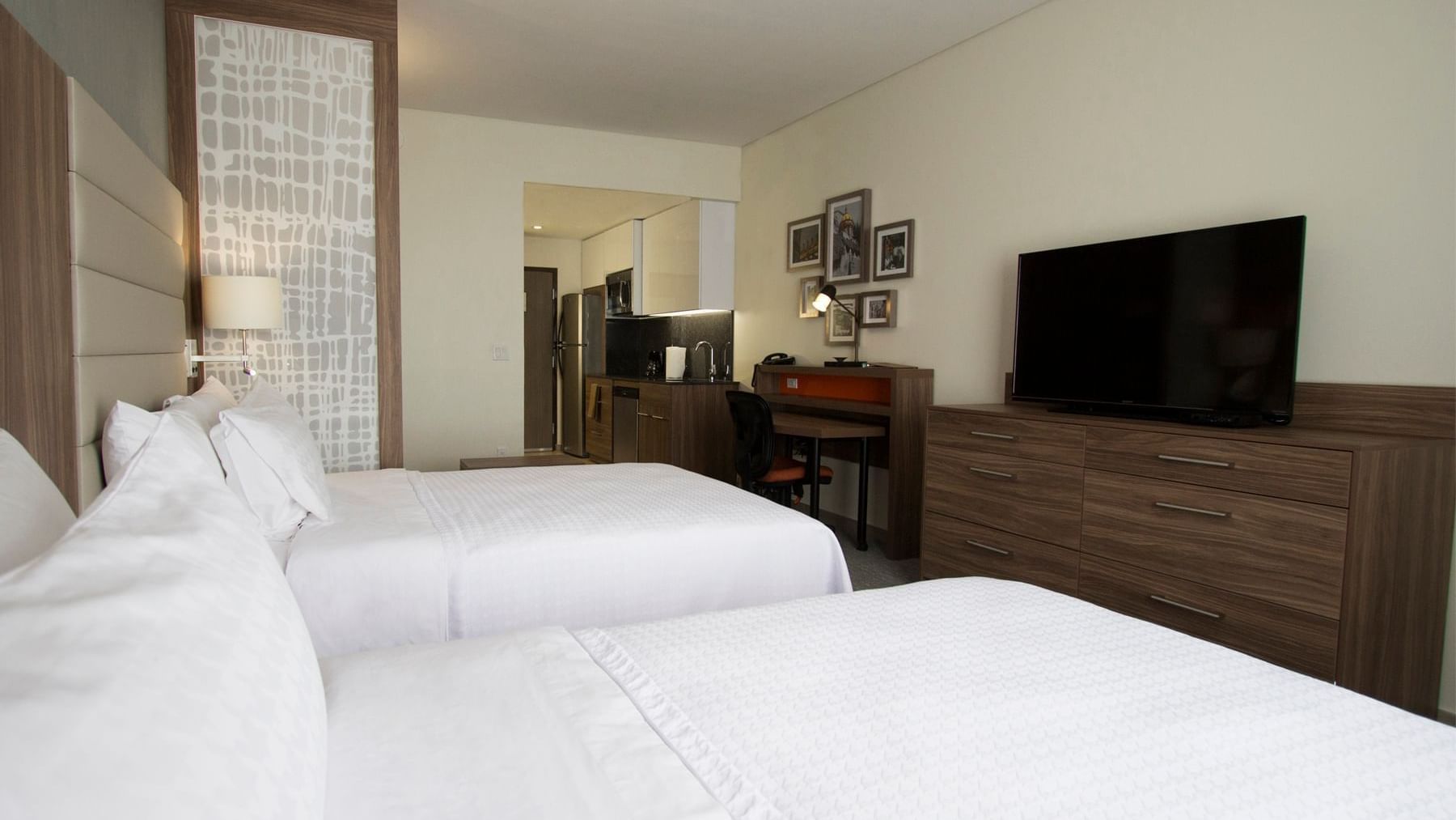 Two cozy beds with a TV in Suite Matrimoniales at Fiesta Inn Suites Aeropuerto del Bajío Silao