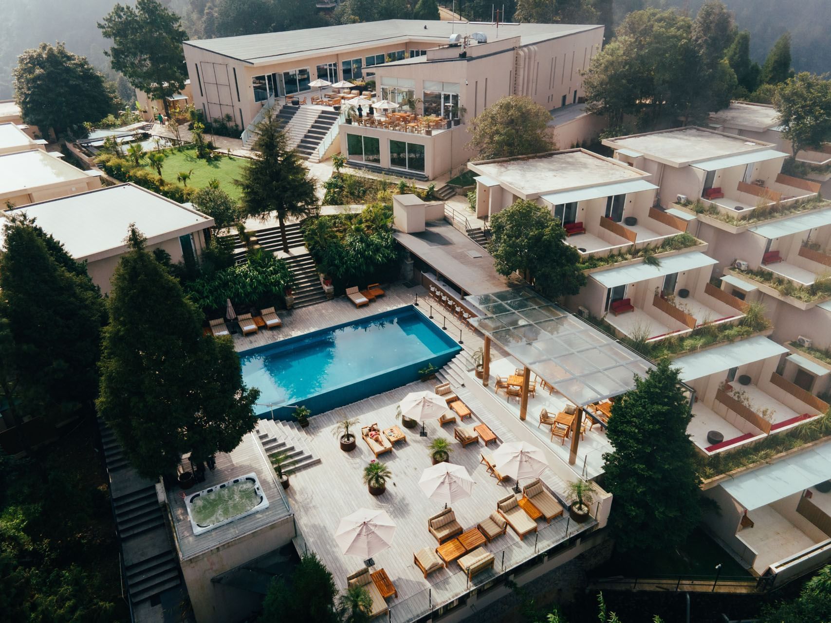 Aerial view of The Terraces Resort & Spa with a pool, lounge chairs, and lush greenery