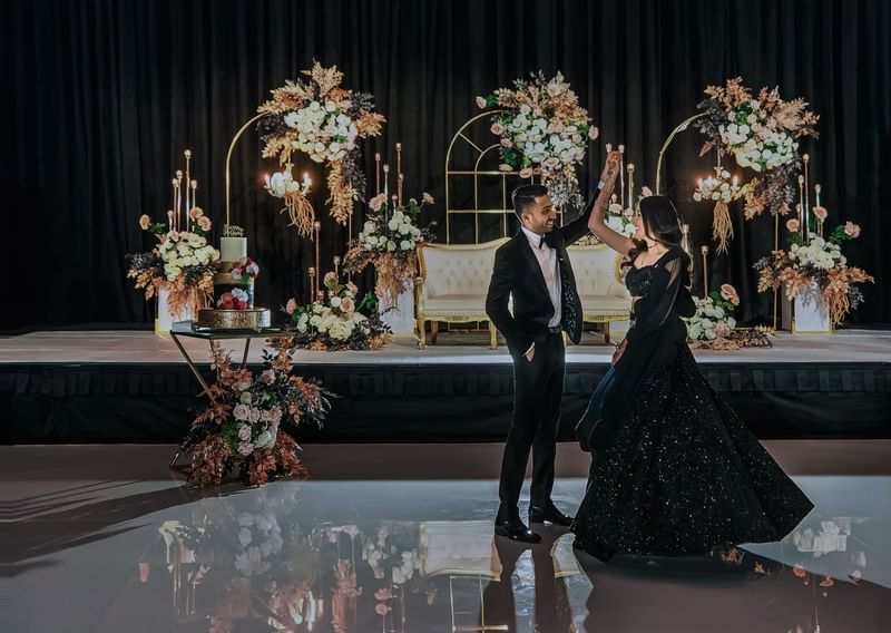 Couple wedding attire dancing by a stage with floral arrangements at Sofitel Brisbane Central