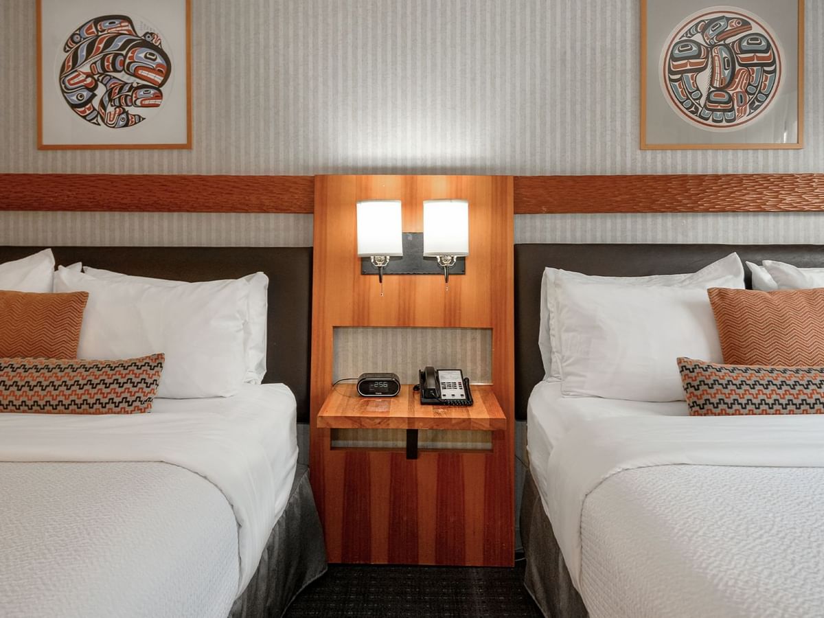 Spacious hotel room with two queen beds, elegant decor and nightstand.