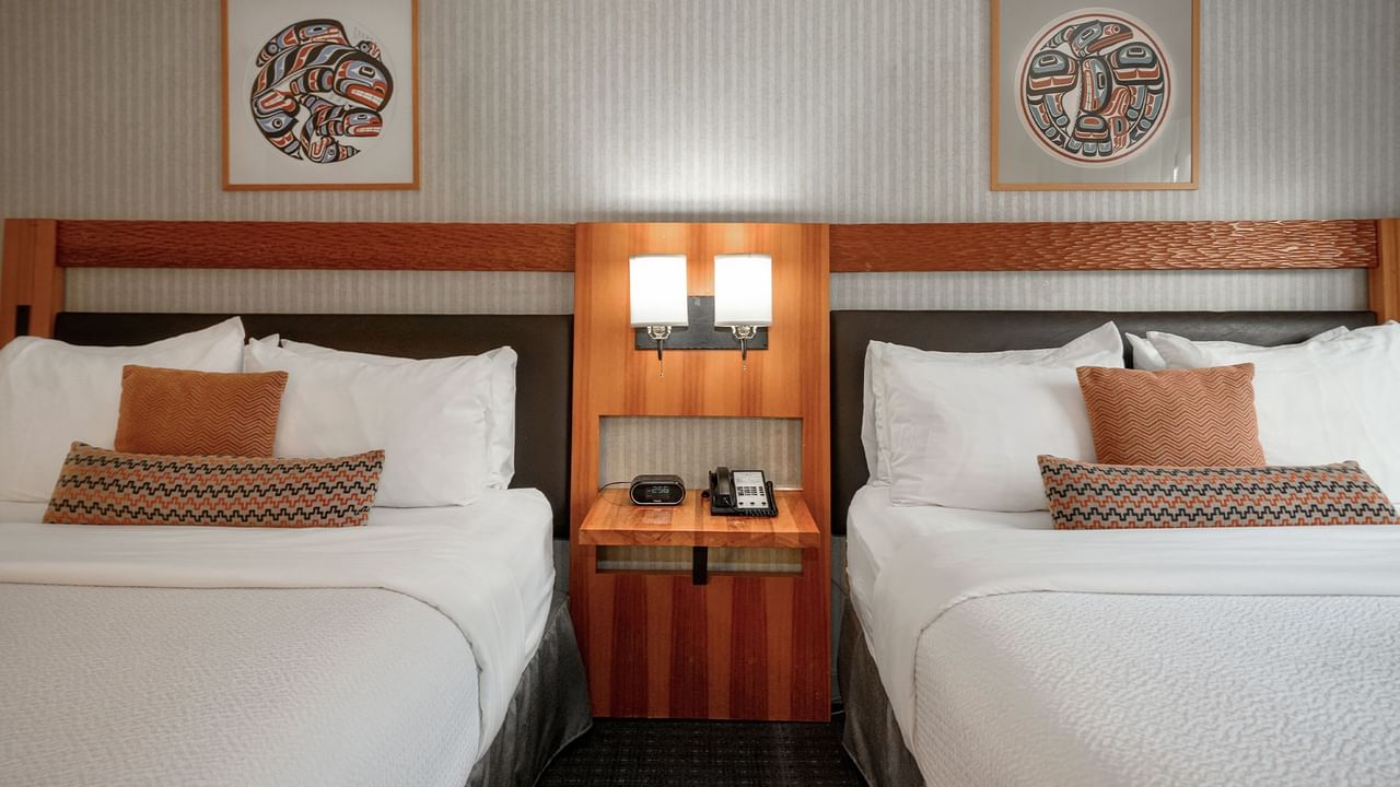 Spacious hotel room with two queen beds, elegant decor and nightstand.