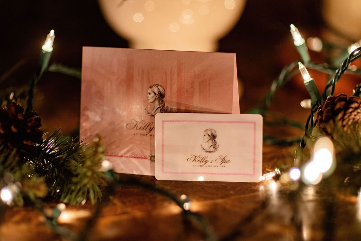 Kelly's Spa gift card and brochure displayed on a rustic surface with festive Christmas lights at Kelly's Spa