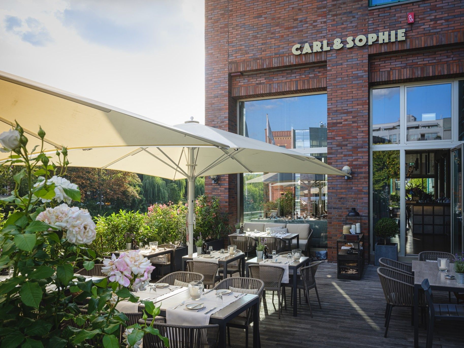 Outdoor dining area with tables and umbrellas at Carl & Sophie in Abion Spreebogen Waterside Hotel Berlin.