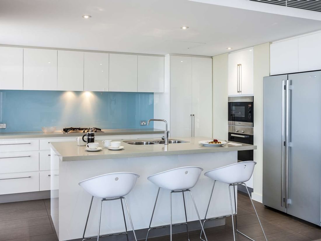 Modern kitchen in Interconnecting Apartment at The Sebel Mandurah with a large island and white bar stools