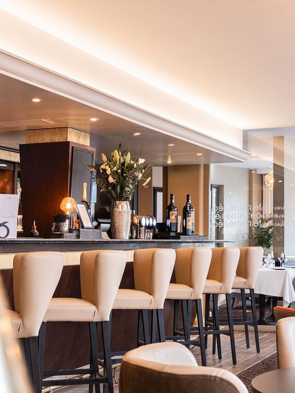 Téséo Bar stools by a dark counter under a floral vase and warm recessed lights at Warwick Geneva