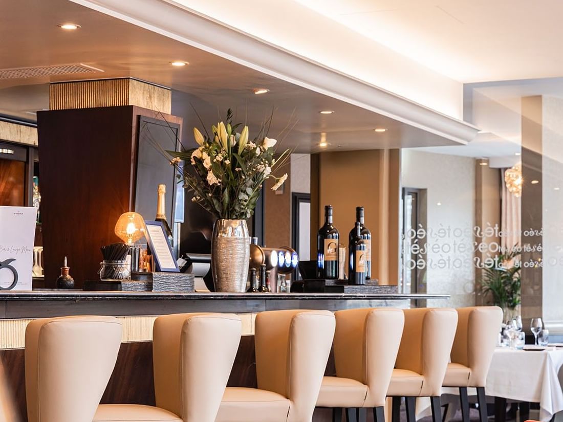 Téséo Bar stools by a dark counter under a floral vase and warm recessed lights at Warwick Geneva