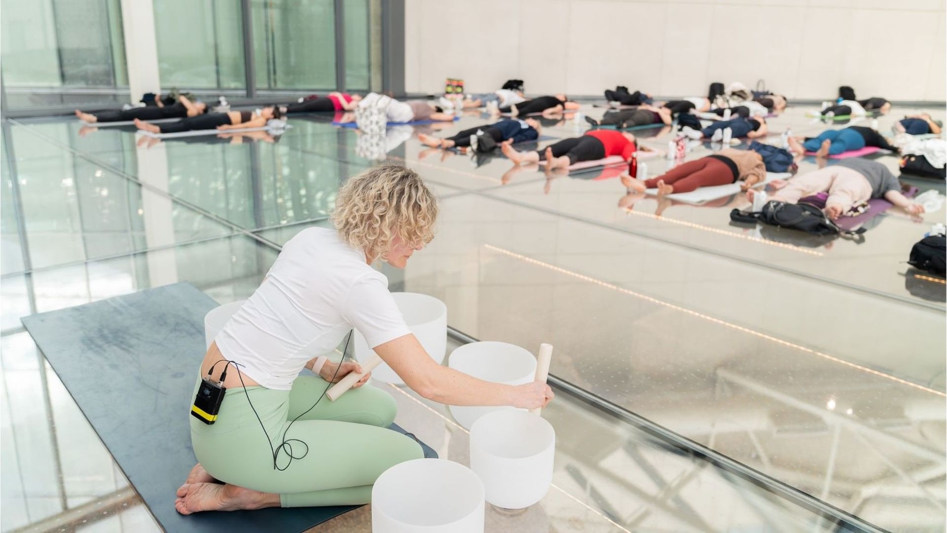 Instructor playing singing bowls as guests rest on yoga mats during a soothing wellness sound bath at Hotel X Toronto