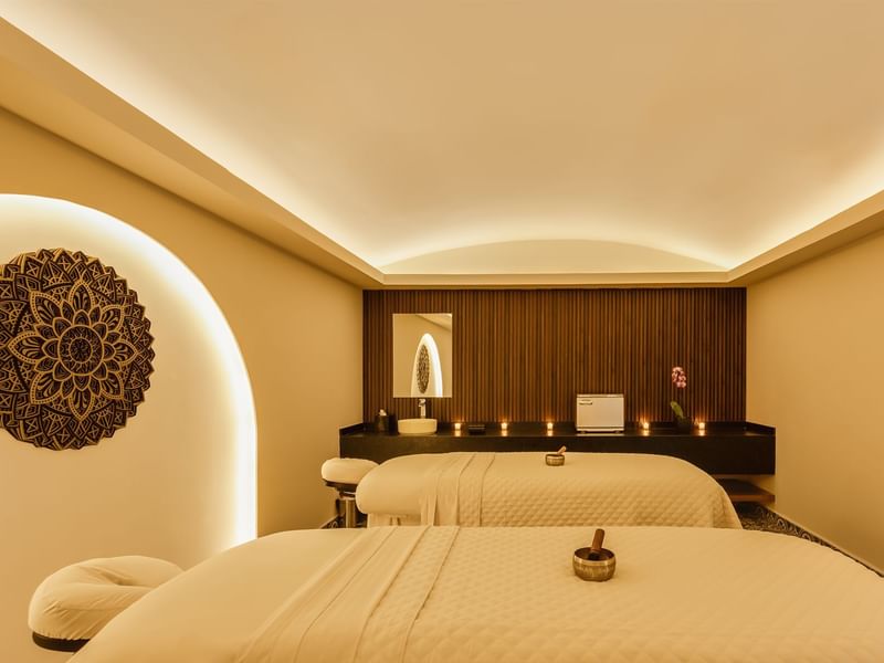 Serene spa treatment room at Fiesta Americana, featuring two massage beds and soft, calming lighting