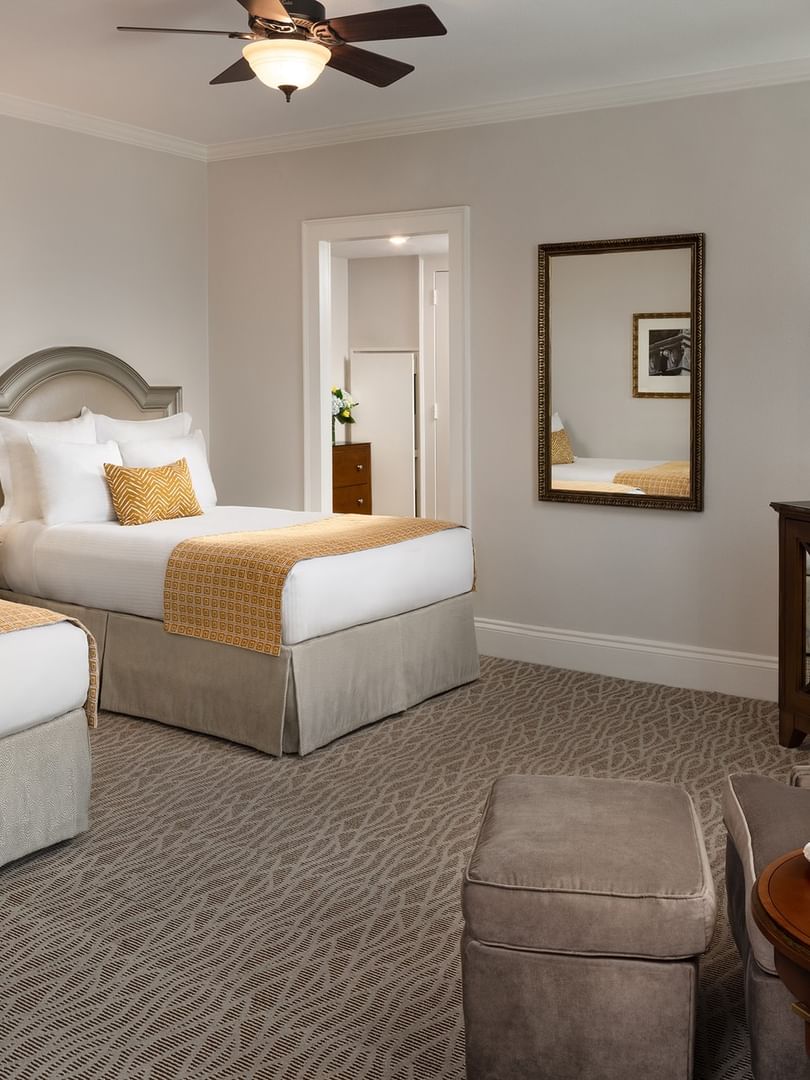 Two double beds by a wood TV stand under a classic ceiling fan in classic double at Warwick Melrose Dallas