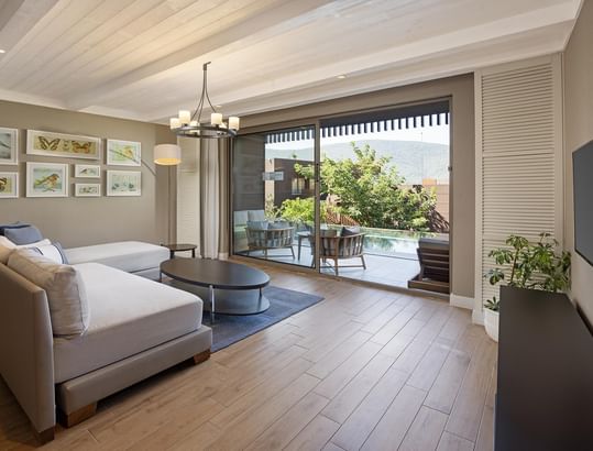 Swim-up Family Suite's modern living room with white sectional sofa, wooden coffee table, rug, and flat-screen TV.