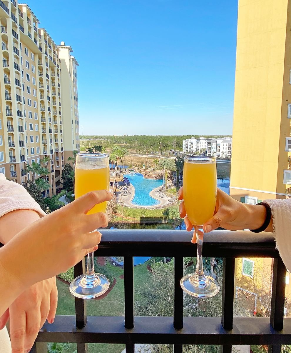 Couple having juice on balcony with pool view of Reflections Spa & Salon at Lake Buena Vista Resort Village & Spa