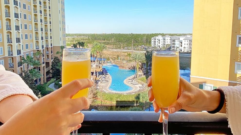 Couple having juice on balcony with pool view of Reflections Spa & Salon at Lake Buena Vista Resort Village & Spa