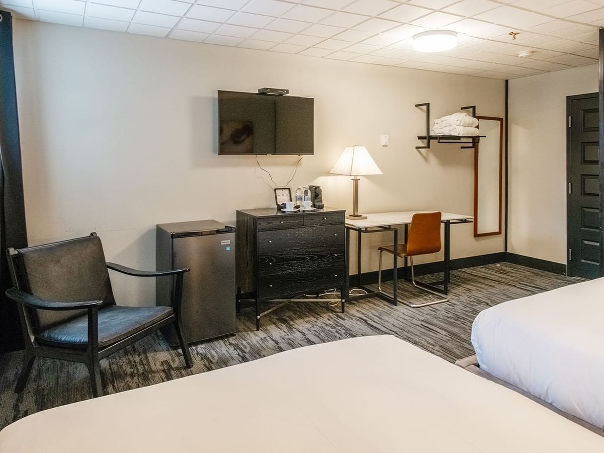 Hotel room with two queen beds, armchair, mini fridge, TV, and work desk