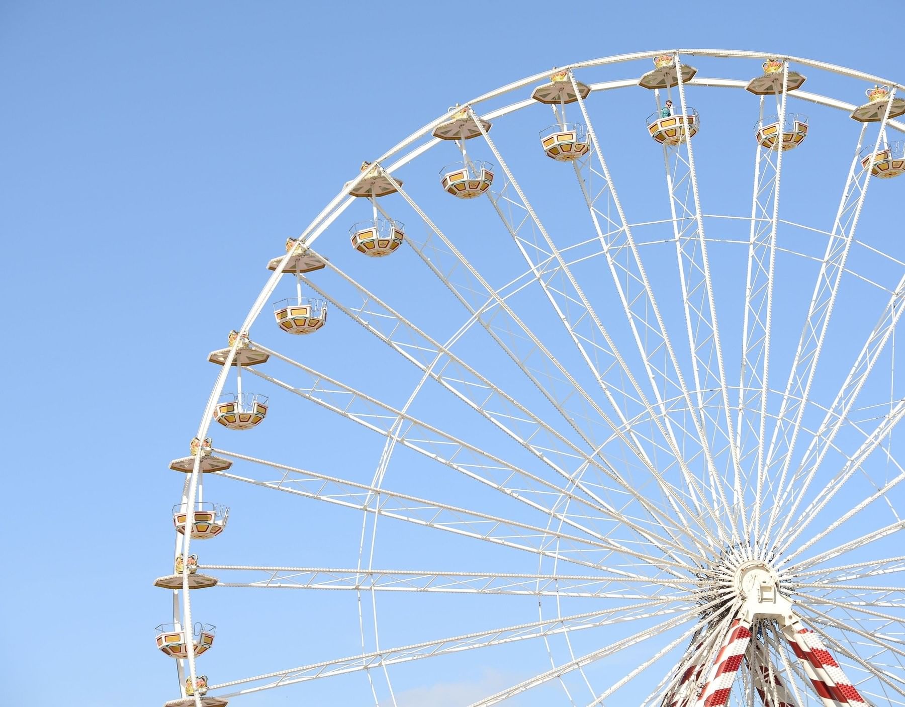 Close-up of a Ferris wheel structure with gold cabins against a blue sky at Old Town Kissimmee near The Inn at Celebration
