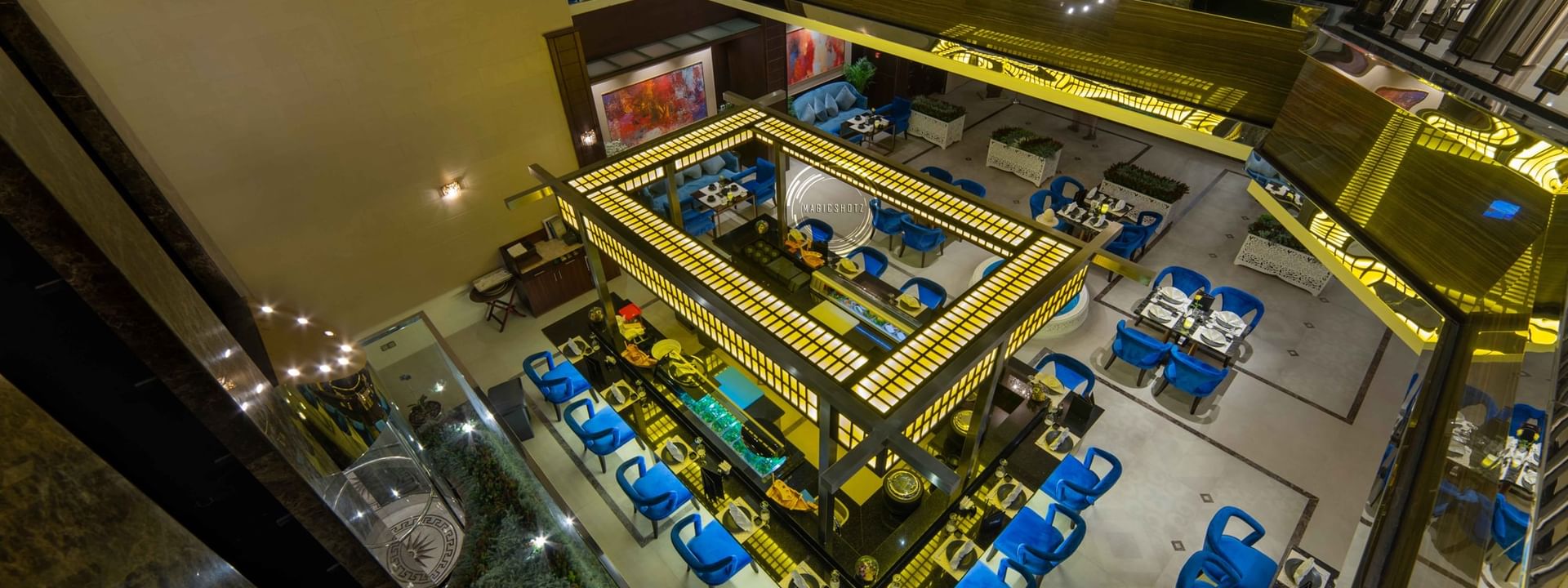 High-angle view of a Taki Restaurant featuring a central illuminated bar surrounded by blue seating at Warwick Al Khobar