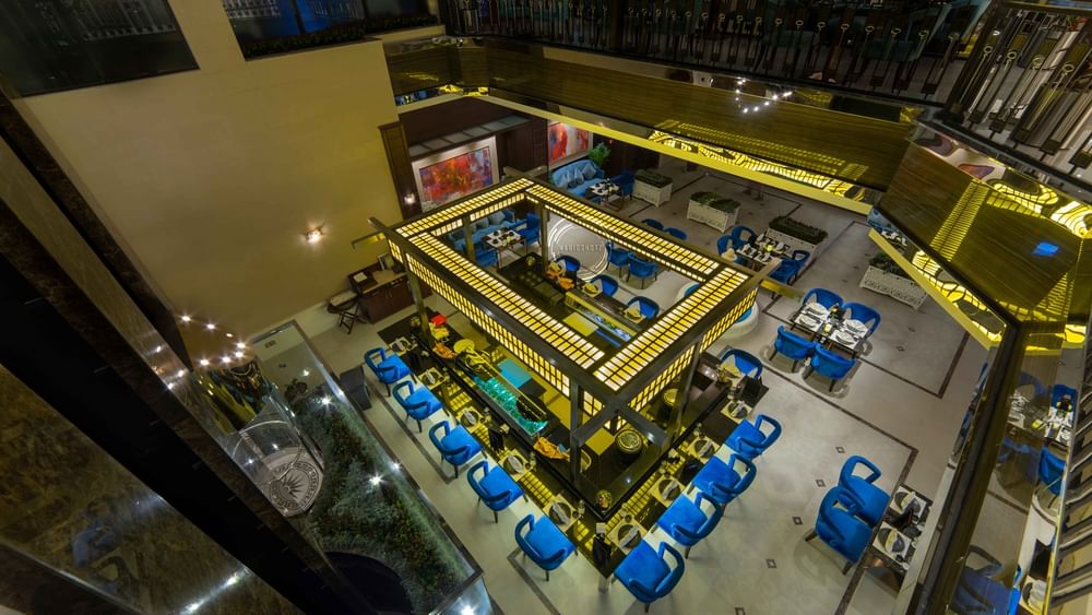 High-angle view of a Taki Restaurant featuring a central illuminated bar surrounded by blue seating at Warwick Al Khobar