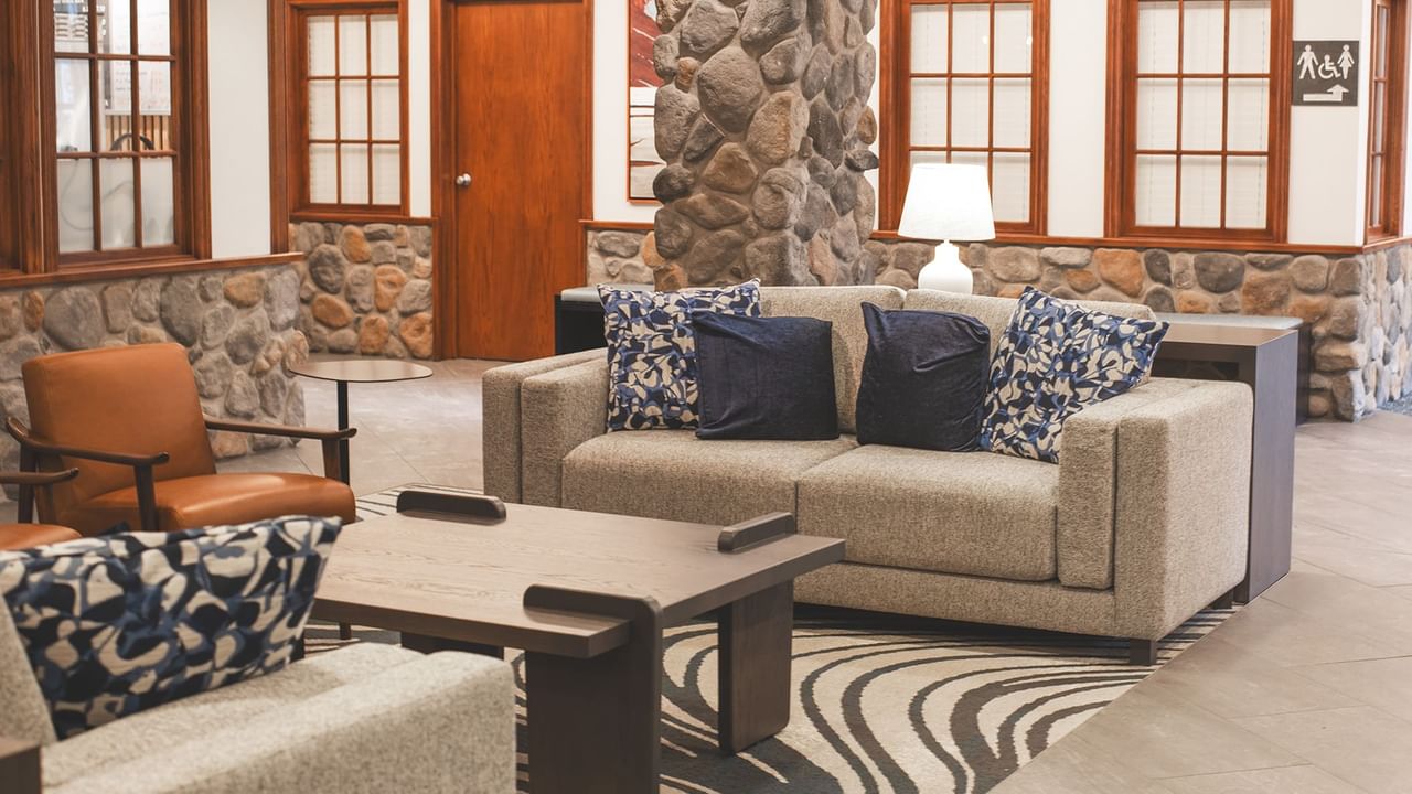 A lounge area with couches, a wooden table, and a stone wall.
