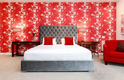 La Rouge Suite with a king bed, striking red wallpaper, and a spacious layout.