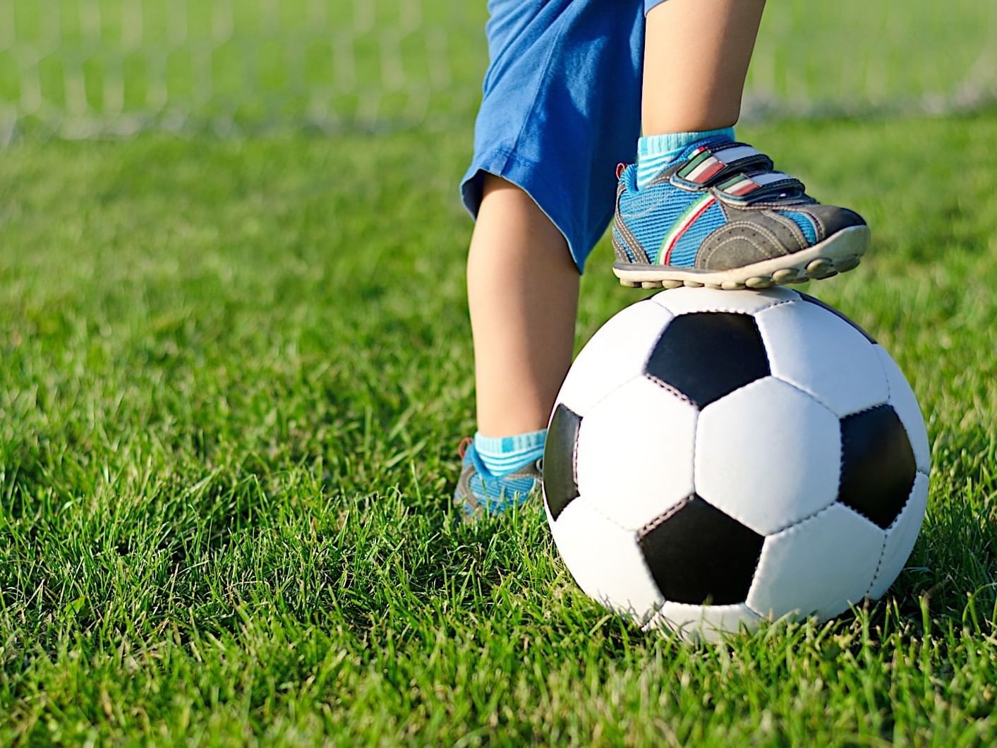 Kid standing with his foot on soccer ball at Mundo Imperial