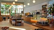 Contemporary café space with natural light, relaxed seating, and grab-and-go offerings.