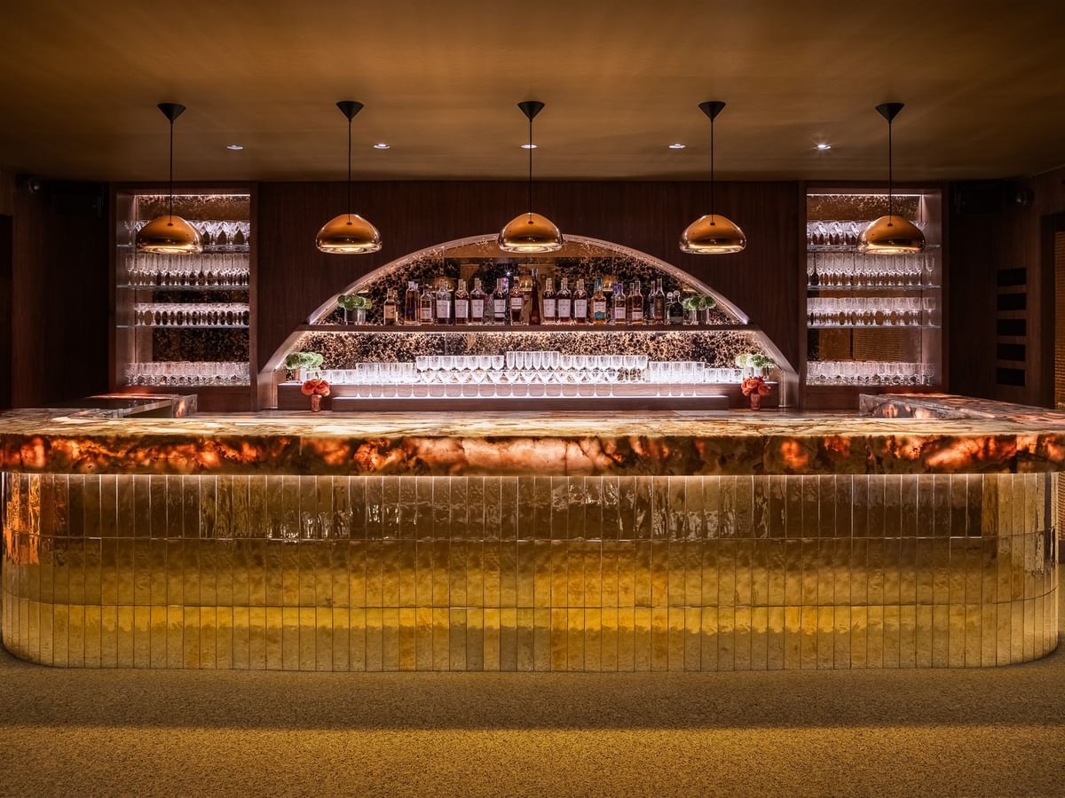 Dimes event room featuring a curved gold-paneled bar with copper pendant lights at Gansevoort Meatpacking NYC - NEW