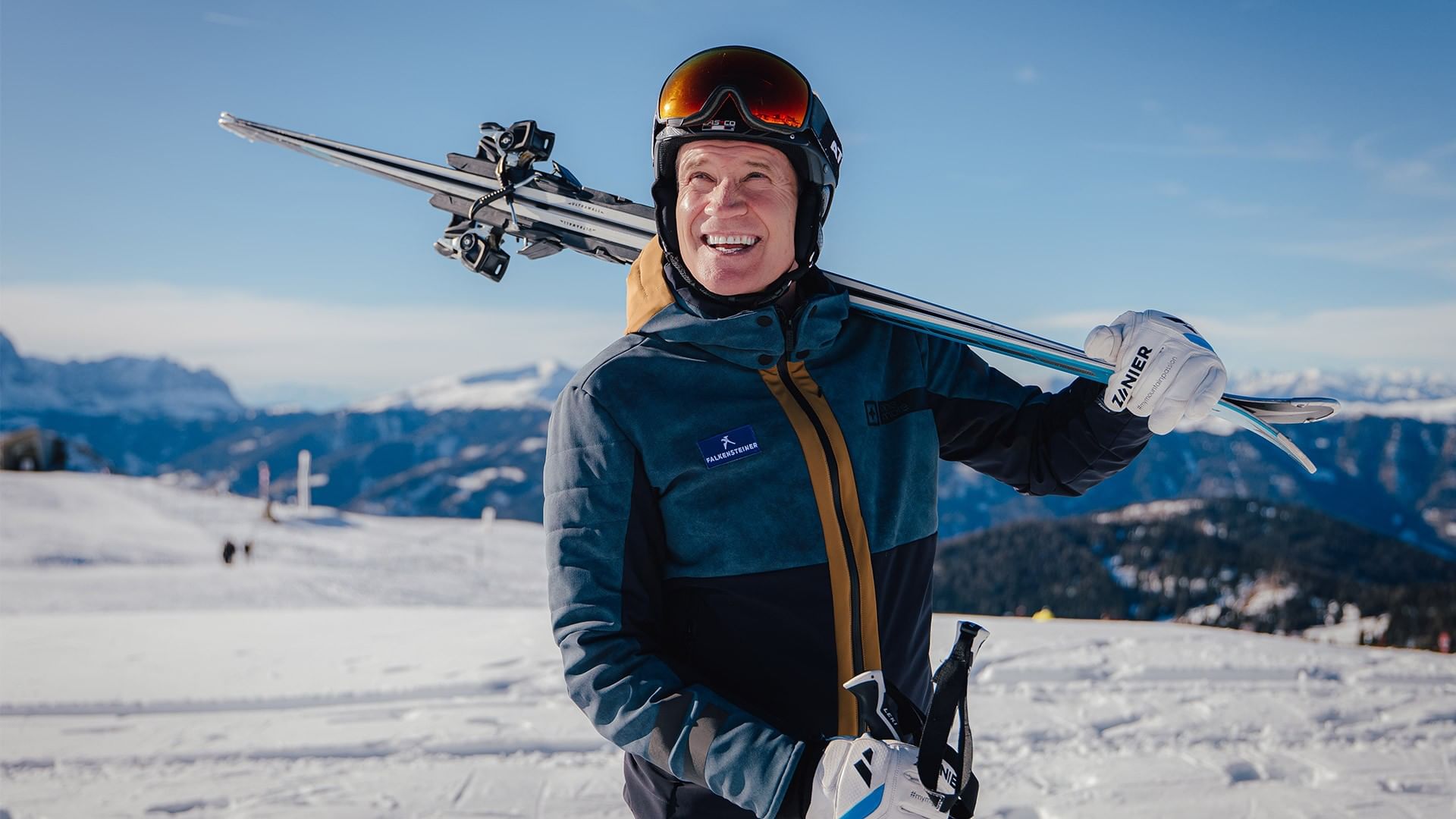 A skier with skis on his shoulder and a smile at Falkensteiner.