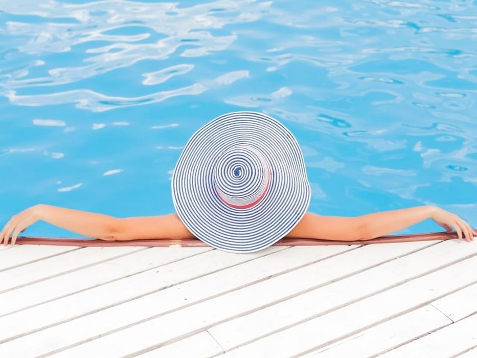 Lady relaxing by a pool, covered with a striped sunhat at York Hotel Singapore