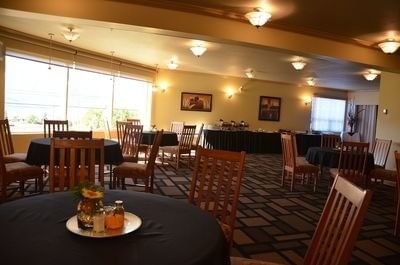 The Okanagan with wooden chairs around black tables, large windows along the wall at Hilltop Inn Salmon Arm
