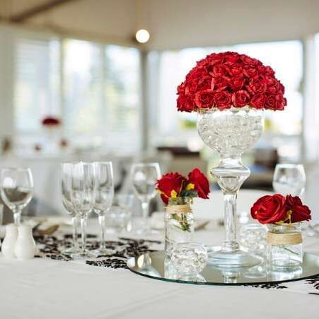Wedding table featuring crystal vase filled with red roses surrounded by glassware at Mercure Hotel Townsville