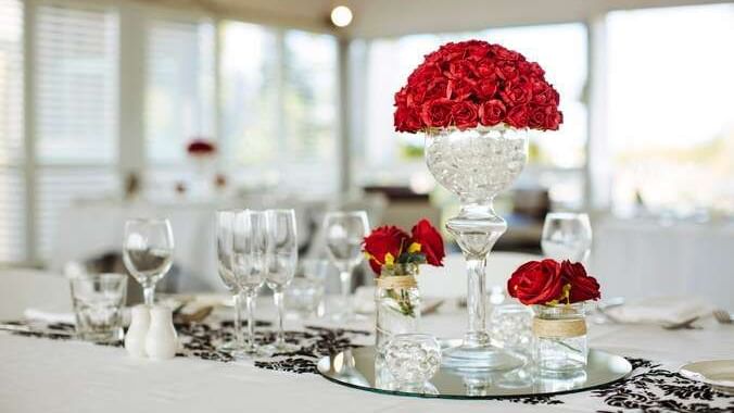 Wedding table featuring crystal vase filled with red roses surrounded by glassware at Mercure Hotel Townsville
