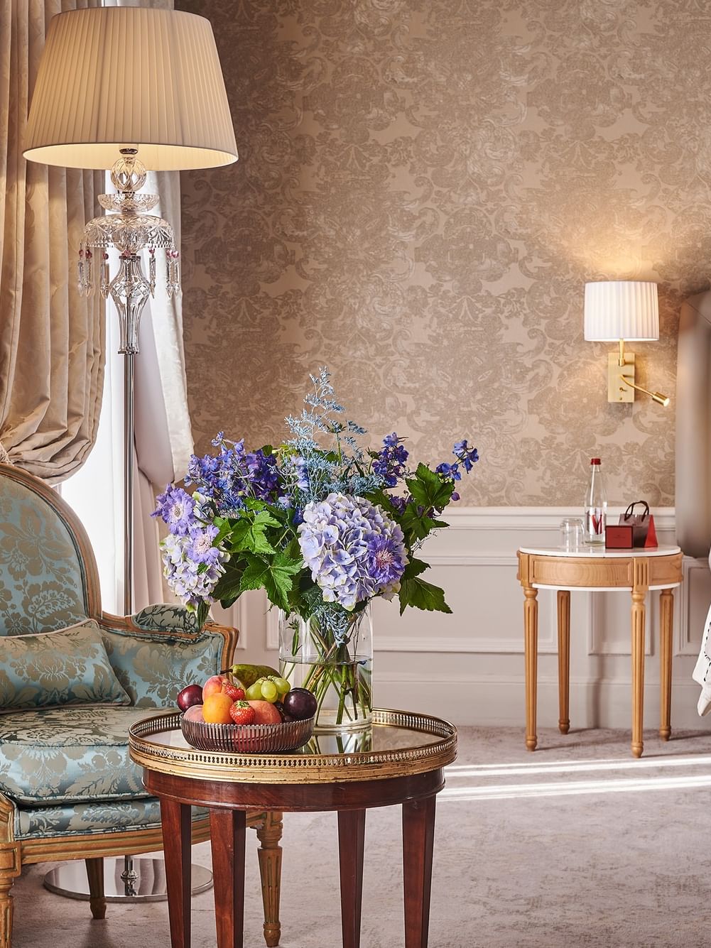 Elegant hotel room with ornate furniture, floral wallpaper, and fresh flowers at Hôtel Westminster.