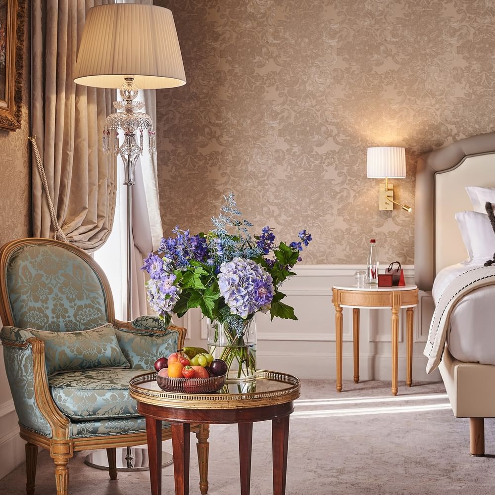 Elegant hotel room with ornate furniture, floral wallpaper, and fresh flowers at Hôtel Westminster