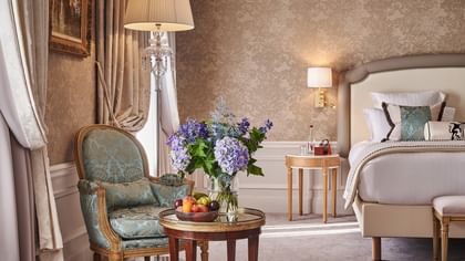 Elegant hotel room with ornate furniture, floral wallpaper, and fresh flowers at Hôtel Westminster