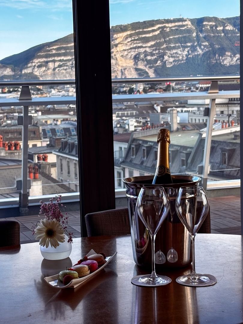Une table à manger avec vue sur la ville et un drapeau suisse dans la suite Penthouse Terrace du Warwick Geneva.