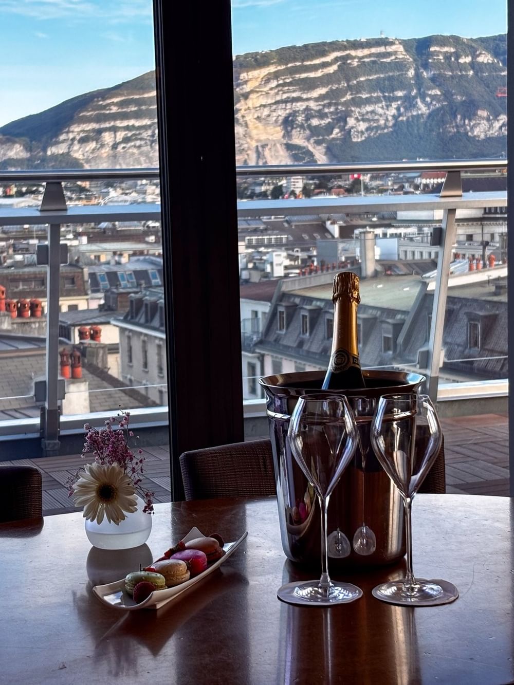 Une table à manger avec vue sur la ville et un drapeau suisse dans la suite Penthouse Terrace du Warwick Geneva.