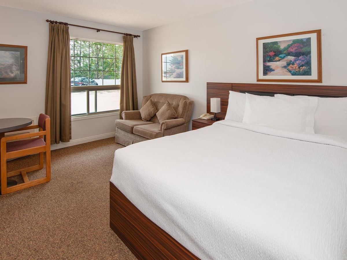 Guest room with a queen bed, work desk, TV and window.