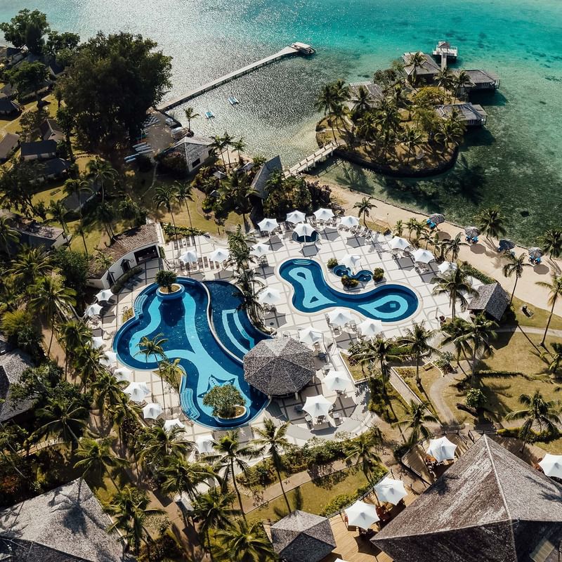 High-angle view of outdoor pool & hotel at Warwick Le Lagon